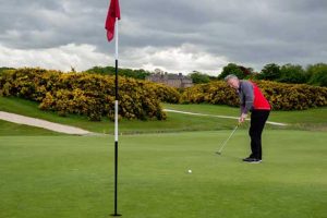 Man putting with flagstick in