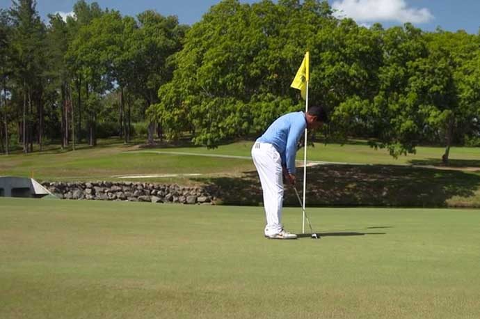 Golfer putting with flagstick in